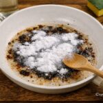 Padella in ceramica con residui bruciati pulita con bicarbonato e acqua su tavolo in legno - Foto Vgai